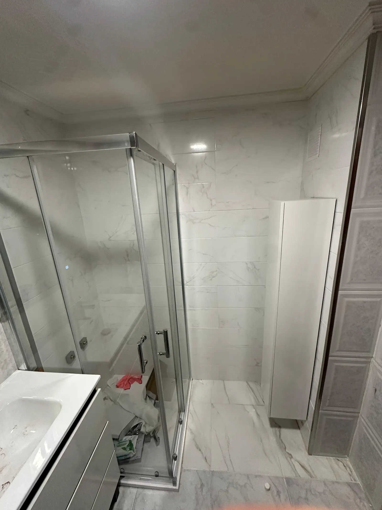 Reforma de baño con mampara de cristal, azulejos efecto mármol y mueble auxiliar en A Coruña