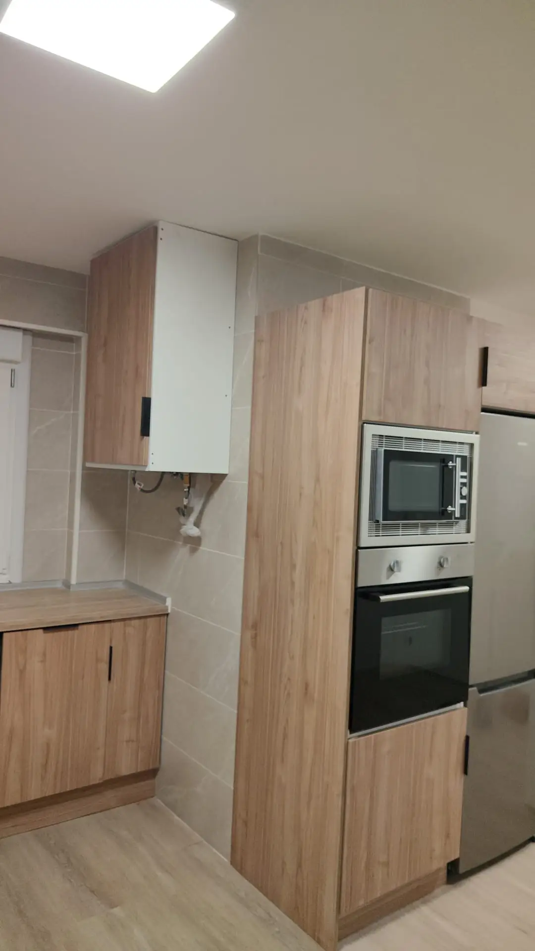 Reforma de cocina con mobiliario en acabado madera y columna de horno microondas en Coruña