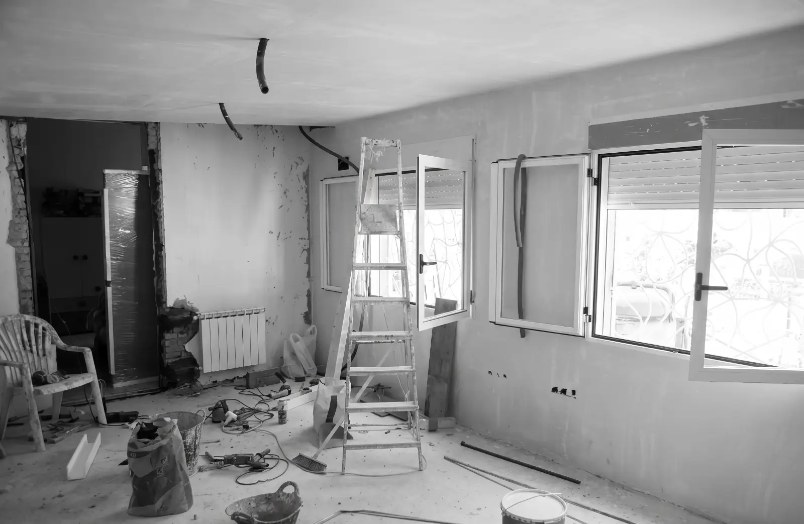 Reforma de vivienda con paredes enlucidas, escalera de aluminio y herramientas de obra en A Coruña