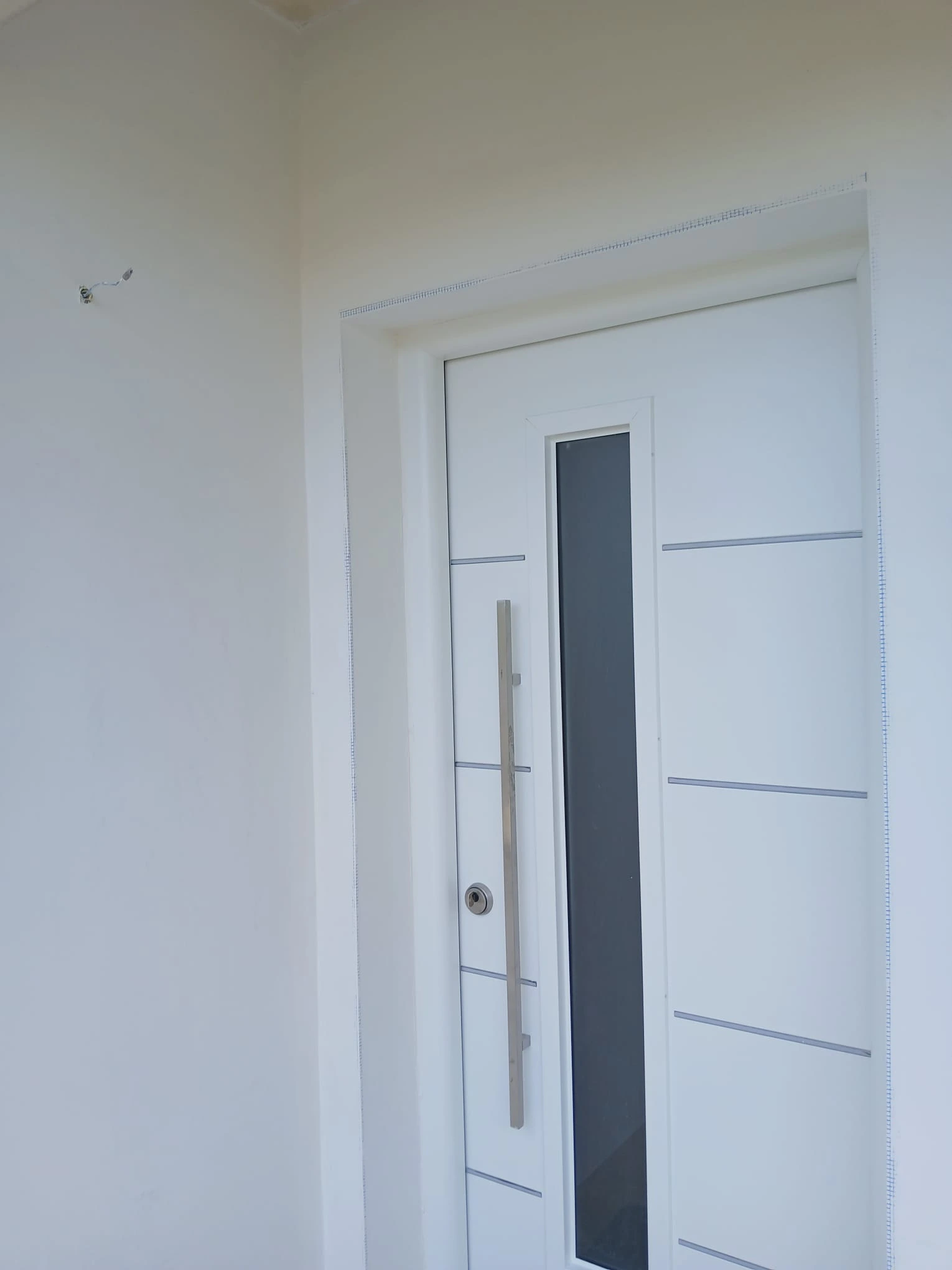 Reforma de vivienda con puerta de entrada blanca moderna y tirador vertical metálico en A Coruña
