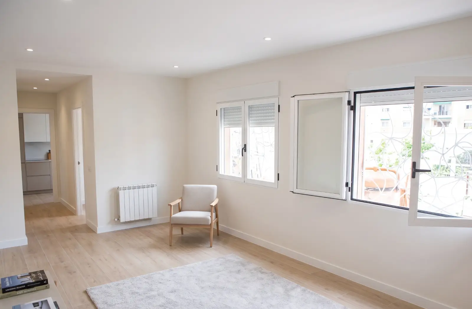 Reforma de vivienda con suelo de tarima clara, paredes blancas y ventanas de aluminio en A Coruña