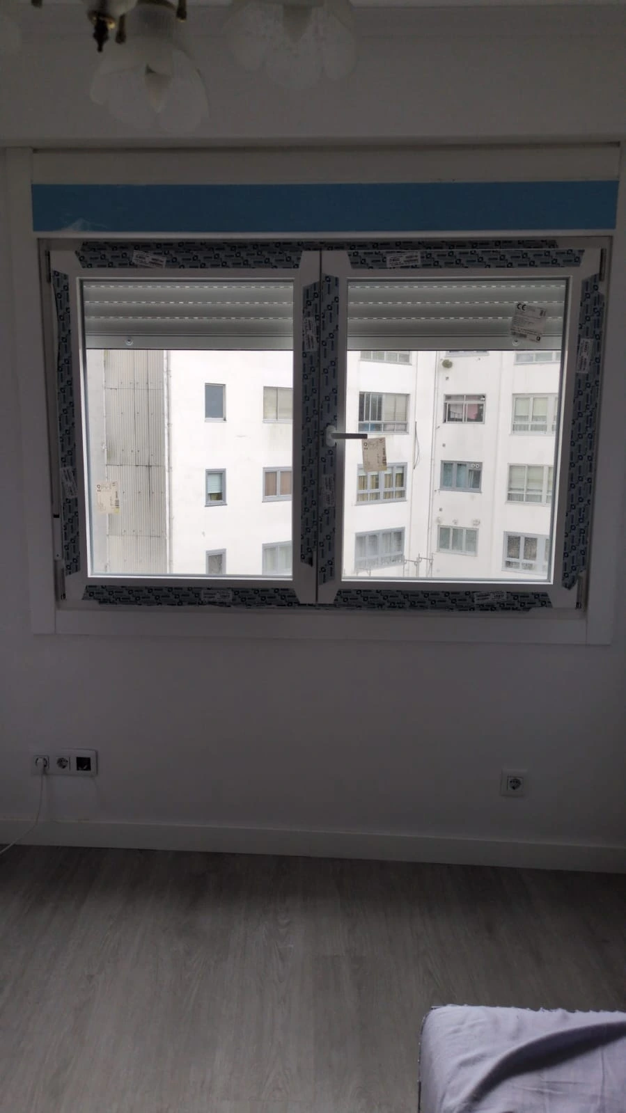 Reforma de vivienda con nueva ventana de PVC blanca y suelo laminado gris en A Coruña
